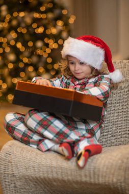 Noel Baba şapkalı çocuk evde Noel ağacının yanında.