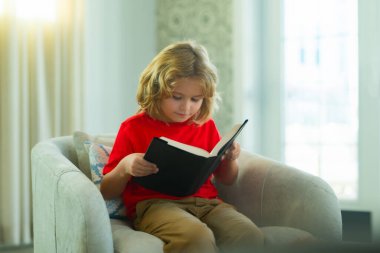 Eğitim kavramı, çocukluk, kitap okuma, sanat eseri, ilham. Genç çocuk evde yalnız kırmızı kitap, çocukluk