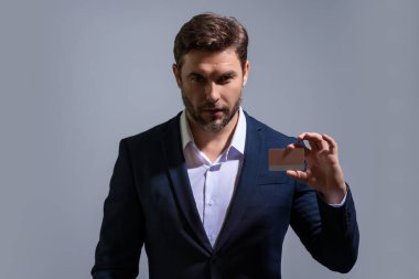 Gri izole arka planda kredi kartıyla takım elbiseli bir iş adamının portresi. Para yönetimi ve kredi puanı. Ödül parası. Kredi limiti. İnternetten alışveriş konsepti. Kredi geçmişi