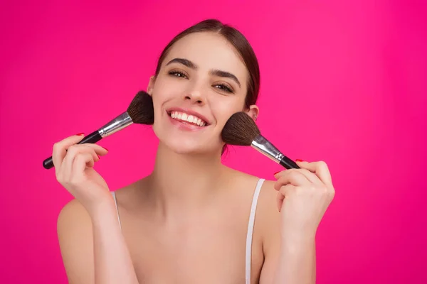 Woman applies powder on the face using makeup brush. Beautiful girl doing contouring apply blush on cheeks. Face beauty cosmetics. Fresh skin and natural make up. Powder blush on facial skin