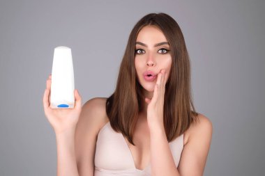 Bir şişe şampuanı olan güzel esmer kız. Parlak saçlı kız. Kadın şampuan ve saç kremi tutuyor. Şampuan şişeli kadın model. Keratin şampuanı, bir şişe şampuan, vücut losyonu.