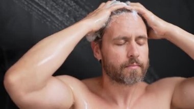 Adam banyoda saç yıkıyor. Küvette banyo yapan adam. Yüzü duşta köpüklü. Banyo yapan adam duş alıyor. Yakından duş alan adam. Duş konsepti. İnsan duşta su altındadır.