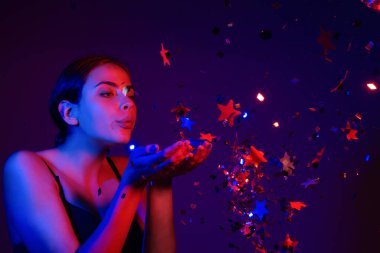 Doğum günün kutlu olsun. Konfeti üfleyen kızın stüdyo portresi. Doğum gününde ya da sevgilisinde konfeti olan güzel kız. Seksi model doğum gününde konfeti üflüyor. Doğum günü esprilerini kutlayan şehvetli kadın.