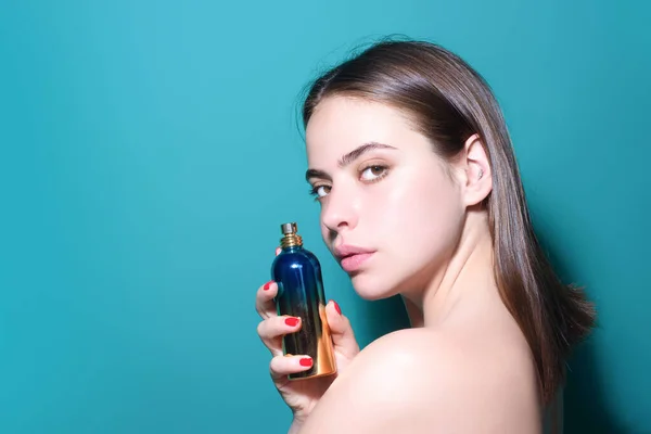 Girl with perfume. Young beautiful woman holding bottle of perfume and smelling aroma. Sensual sexy girl applying perfume. Beautiful girl using perfume. Woman with bottle of perfumes