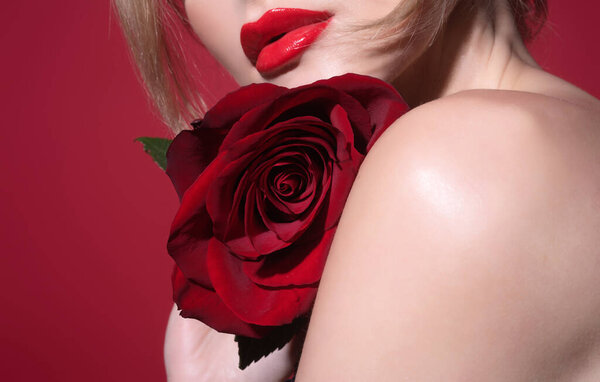 Red lips with red lipstick. Studio beauty portrait of young beautiful sexy woman with red rose flower