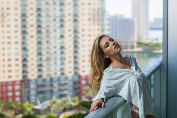 Rich woman enjoying morning on the balcony at luxury apartments in Miami. Luxury life concept. Sexy sensual woman enjoys of rest. Urban lifestyle. Relaxation lifestyle on summer holiday vacation