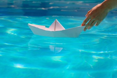Elle kağıt tekne. Mavi su yüzeyinde yüzen kağıt tekne.