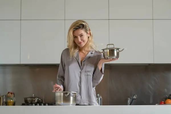 Sexy woman in the kitchen in the morning and cooking healthy food. Woman with cooking pot. Sensual housewife