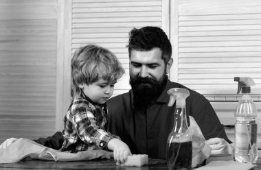 İnsan ve çocuk toz alıyor. Baba ve oğul oturma odasını birlikte temizliyor.