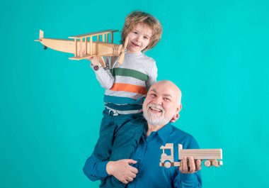 Yaşlı büyükbaba ve küçük torunun oyuncak uçakları ve tahta kamyonları var. Erkek nesli büyükbaba ve torun