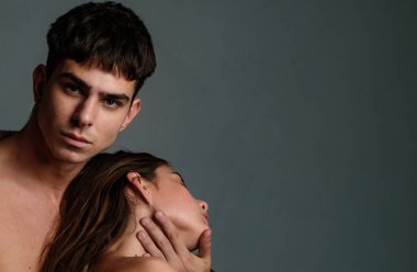 Gri arka planda moda çifti, kopyalama alanı. Moda kurbanı. Birbirine aşık çiftler. Cilt bakımı ve saç bakımı. Modern hayattaki ilişki. Yumuşak ten. Kabarık saçlı. Güzel ve yakışıklı. Erkek ve kadın..