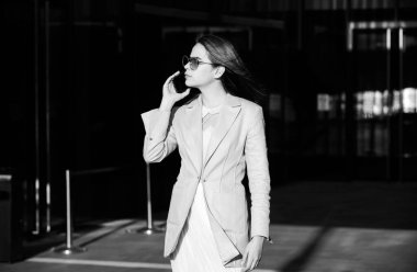 Havalı yaz bahar kıyafetleri içinde dışarıda telefonda konuşan güzel bir iş kadını. Kadın stili model şehir caddesinde yürüyor. Yaz trendi, moda kıyafeti