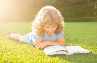 Akıllı çocuklar. Küçük çocuk yaz gün batımında kitap okuyor. Açık hava çocuk eğitimi