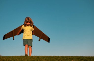 Çocuk roket pilotu olmayı hayal ediyor. Hayal gücü ve motivasyon konsepti. Mutlu çocuk mavi gökyüzü arka planında oyuncak uçakla oynuyor.