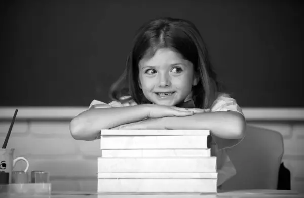 学校に戻る 笑顔の女の子は机の上に座って学校の教室で本を手に — ストック写真