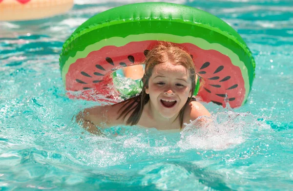 Kid swim in swimming pool. Water sport activity on summer vacation with children. Funny kids summer face