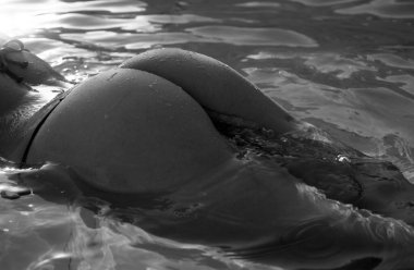 Sensual bum in swimming pool close-up, summer journey, woman with hot natural butt relax in water. Wet body, backside in sexy bikini. Seduction and pleasure model. Luxury passion buttocks