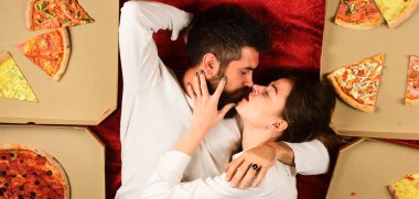Sexy couple eating pizza in bed at home. Couple sharing pizza and eating together. Passionate couple. Young lovers. Couple in love.