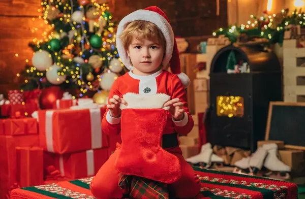 クリスマスのストッキング 靴下にクリスマスプレゼントの小さな男の子 新年明けましておめでとう 屋内だ メリーと明るいクリスマス 子供の頃の記憶 素敵な赤ちゃんは休日を楽しむ — ストック写真