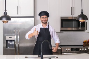 Aşçı, aşçı ya da fırıncı portresi. Aşçı şapkalı ve aşçı üniformalı adam mutfakta yemek pişiriyor.