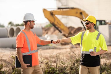 İnşaat ekipmanlarıyla başarılı inşaat işçileri. Miğferli inşaat işçileri inşaat projesinde çalışıyor. İnşaat alanında kasklı iki işçi.