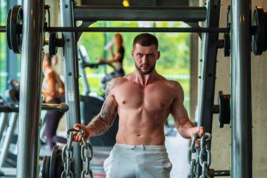 Ağırlık metal zincirlerle egzersiz yapan bir adam. Uygun model ağırlık kaldırma zinciri, spor salonunda egzersiz. Zincirlerle çalış. Güçlü, kaslı, formda, zincirleri ve ağır ağırlığı olan bir adam. Pazılar için alıştırmalar