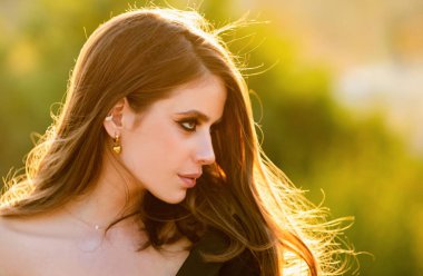 İlkbahar romantik kadın portresi. Açık havada güzel bir kız, genç ve güzel bir kadının yüzünü kapatıyor. Genç bayan gün ışığının tadını çıkarıyor.