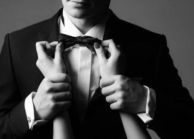 Centilmen kıyafeti. Kadınların elleri kravatı düzeltir. Erkek modası. İş görünüşü. Zarif ve şık kıyafetler.