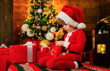 İçinde hediye kutusu olan mutlu küçük bir çocuk. Noel Baba şapkalı mutlu çocuk, afiyet olsun.