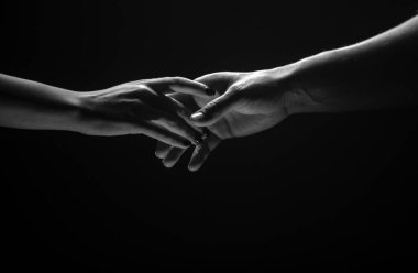 İki el birbirini gerer, siyah arka plan. Birbirine aşık çiftler, yaklaşın. Yardım eli, destek, arkadaşlık