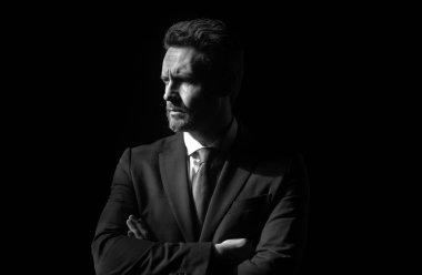 Siyah üzerine izole edilmiş zarif yakışıklı bir iş adamının portresi. Yakışıklı, orta yaşlı, takım elbiseli bir işadamı fotokopi alanı olan siyah bir arka plana karşı poz veriyor. Olgun iş adamı