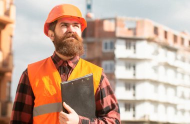 İnşaatçının portresi. İş kıyafetli ve miğferli bir erkek inşaat işçisi.