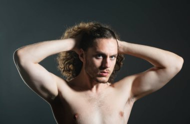 Çıplak gövdeli ve kıvırcık saçlı bir adam. Gri arka plan fotokopi alanında izole edilmiş mükemmel kıvırcık saçlı çekici, kaslı esmer adamın yakın portresi.