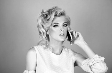 Telefonla izole edilmiş pembe arka planı olan genç bir kadın. Akıllı telefonu olan genç sarışın kadın.