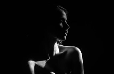 Şefkatli kız, şefkat. Siyah arka planda poz veren zarif genç bir kadın. Işık ve gölge. Güzel bir kadının portresi.