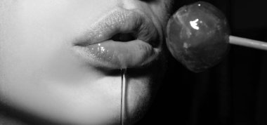 Seksi oral seks sembolü. Ağız yalayan lolipop, kırmızı kadın parlak dudakları ve pembe şeker lolipopu. Orgazm kavramı