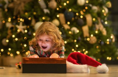 Sürpriz çocuk hediye kutusunu açıyor. Evdeki noel ağacının yanındaki çocuk.