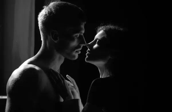 Beautiful loving couple posing on dark backgroung with night lights. Close up face of a beautiful young couple in love embracing, romance and and affection