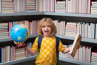 Heyecanlı öğrenci. Dünya küresi ve satrancı olan okul çocuğu, çocukluk. Küçük okul çocuğu. Okul malzemeleriyle inek öğrenci portresi.