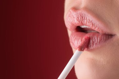 Kız fırçayla dudaklarına ruj sürüyor. Rujlu kadınların dudaklarına yakın çekim. Dudağına ruj sürüyorum. Profesyonel ruj.