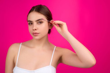 Koyu kaşlı güzel bir kadın kaş fırçası tutuyor. Kaş kaplaması. Güzellik prosedürlerini uygula. Sütyenli kaşlar, maskara göz çizgisi.