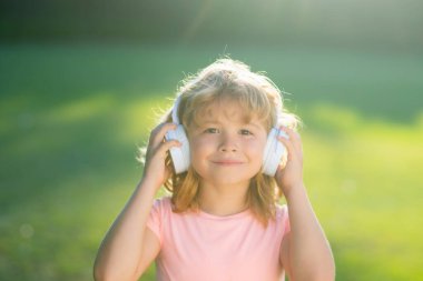 7-8 yaşlarında, tişörtlü ve kulaklıklı eğlenceli bir çocuk müzik dinler. Çocuk yaşam tarzı konsepti