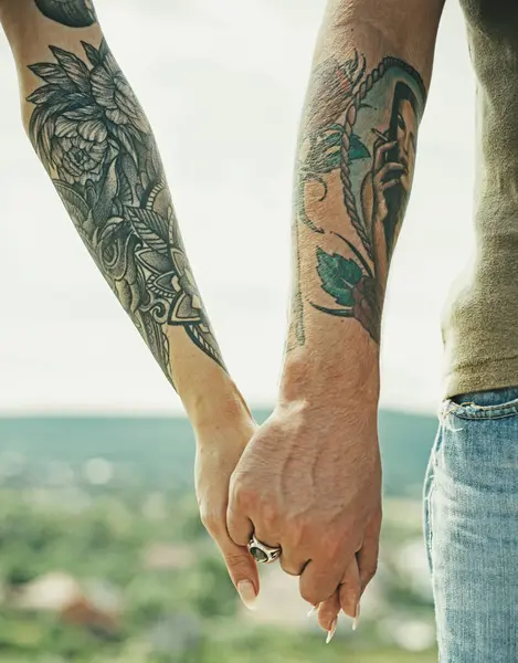 Couple hands with tattoo. Helping hand. Holding hand, close up. Giving a help hand. Rescue, helping gesture or hands. Salvation relations. Help gesture or hands. Support hand