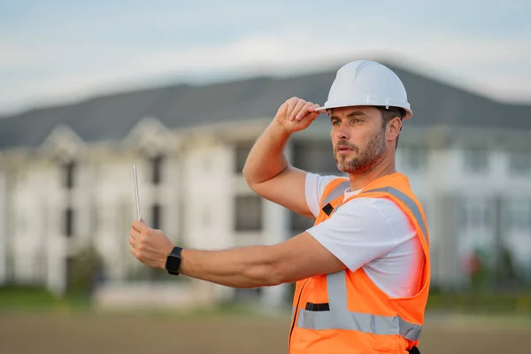 Portrait of builder man. Construction worker with hardhat helmet on construction site. Construction engineer worker in builder uniform. Worker construction