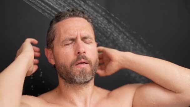 お風呂で髪を洗っている筋肉の男性 バスタブでシャワーヘッドを浴びる男 シャワーで泡立ちする シャワーを浴びている男性 クローズアップの男がシャワーを浴びている シャワーコンセプト 男はシャワーで水滴下にいる — ストック動画