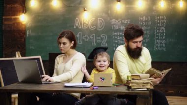 Baba ve anne sevgili oğluna resim çizmeyi ve resim yapmayı öğretiyor. Aile eğitimi. Genç anne baba ve küçük anaokulu çocuğu birlikte masa başı çizimleri yapıyorlar.