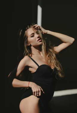 Siyah arka planda poz veren zarif genç bir kadın. Işık ve gölge. Güzel bir kadının portresi. Moda mankeni, zarif kızın siyah modası. Yüksek moda görünüş