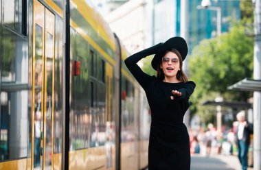 Şehir caddesinde tramvay otobüsünün peşinden koşan güzel genç bir kadın. Güzel, genç bir moda kadını. Şehirde seyahat etmek.