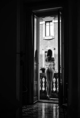 Güzel genç bir kadın balkonda sabahın tazeliğinin tadını çıkarıyor. İyi sabahlar. Seksi popolu güzel kız. Çekici. Uzayı kopyala Güzellik anlayışı. Erotik iç çamaşırlı kadınlar