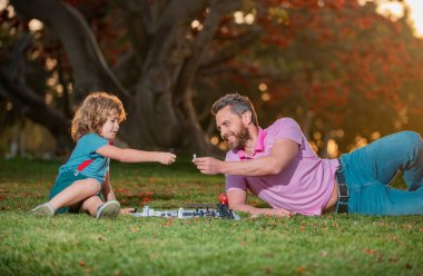 Oğlum çimlere uzanıp babasıyla satranç oynuyor. Akıllı çocuk, akıllı çocuklar.